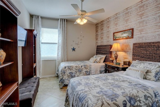 bedroom with ceiling fan, wood walls, and light tile patterned floors