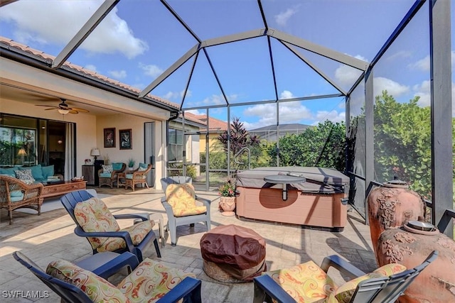 view of patio / terrace with ceiling fan, a hot tub, an outdoor hangout area, and glass enclosure