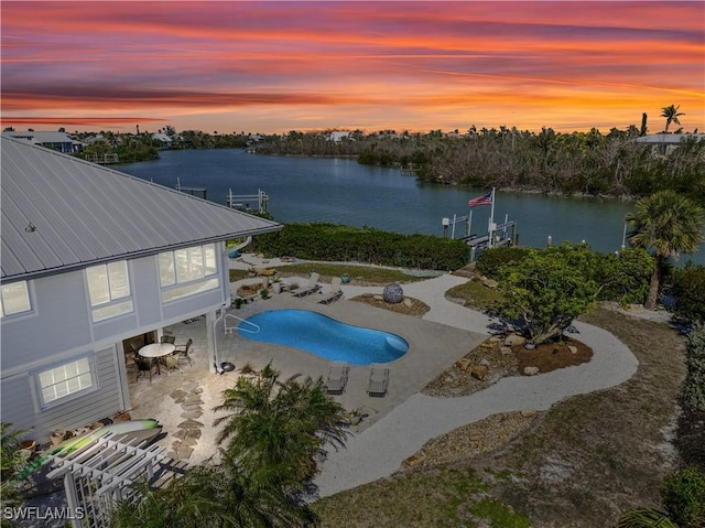 pool at dusk with a patio and a water view