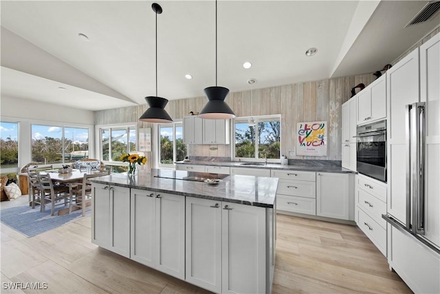 kitchen with a kitchen island, decorative light fixtures, white cabinetry, oven, and black electric stovetop