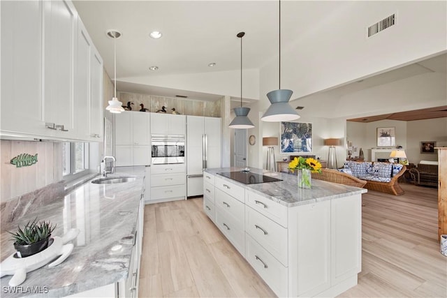 kitchen featuring white cabinetry, black electric stovetop, a center island, and sink