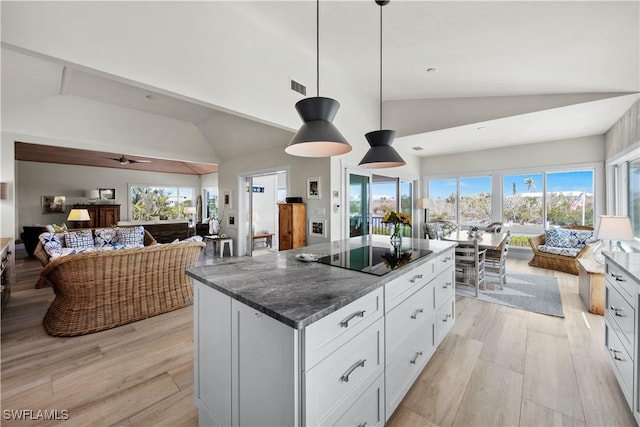 kitchen with white cabinetry, hanging light fixtures, a center island, black electric cooktop, and light hardwood / wood-style flooring