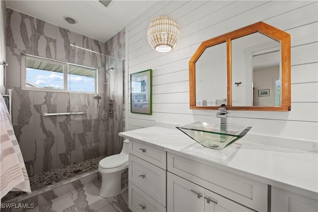 bathroom featuring vanity, a tile shower, wood walls, and toilet