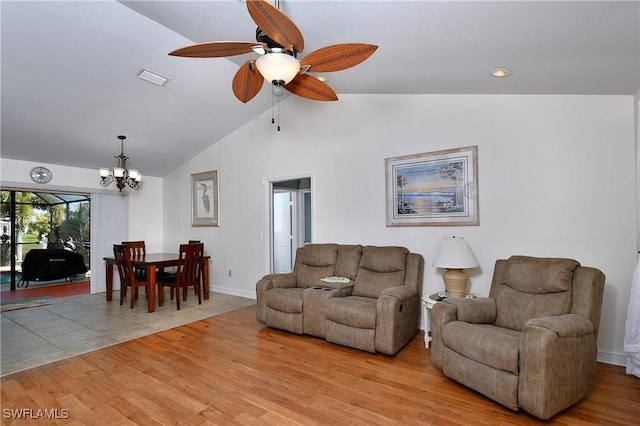 living room featuring ceiling fan with notable chandelier, vaulted ceiling, and light hardwood / wood-style flooring