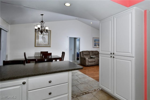 kitchen featuring white cabinetry, vaulted ceiling, hanging light fixtures, and light tile patterned floors