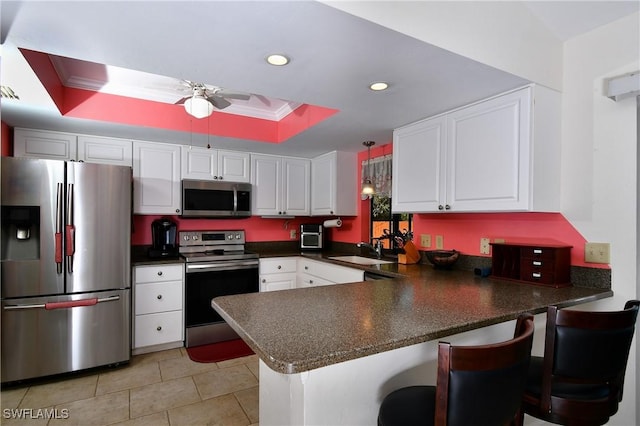 kitchen with white cabinets, kitchen peninsula, a raised ceiling, and appliances with stainless steel finishes