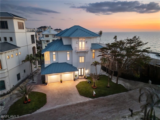 view of front of home featuring a water view, a standing seam roof, metal roof, a garage, and driveway