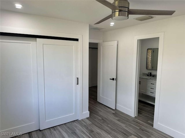 unfurnished bedroom featuring hardwood / wood-style flooring, connected bathroom, ceiling fan, and a closet