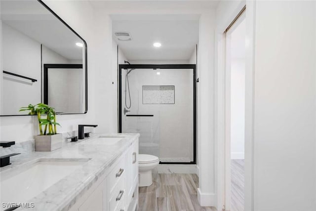 bathroom with hardwood / wood-style flooring, vanity, a shower with shower door, and toilet