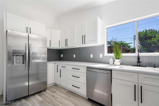 kitchen featuring stainless steel appliances, decorative backsplash, and white cabinets