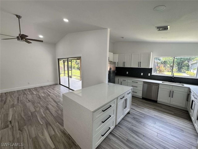 kitchen with a kitchen island, tasteful backsplash, sink, white cabinets, and stainless steel appliances