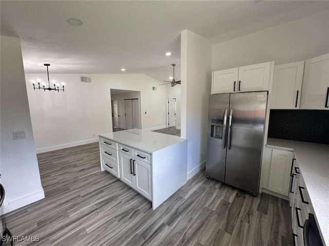 kitchen with hanging light fixtures, vaulted ceiling, white cabinets, and stainless steel refrigerator with ice dispenser