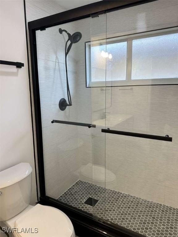 bathroom featuring toilet and a shower with shower door