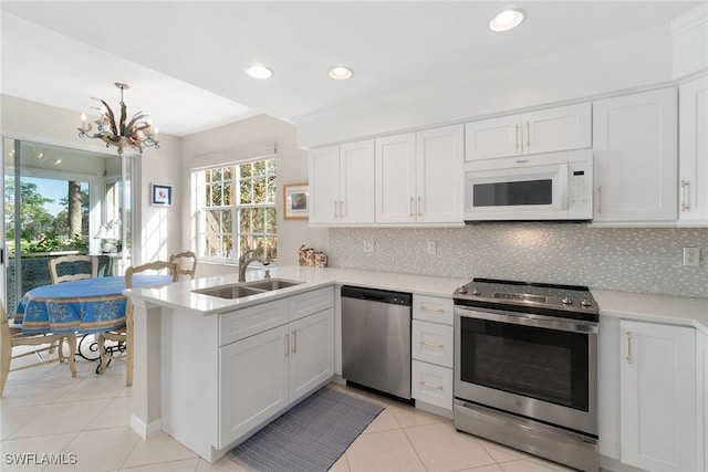 kitchen with appliances with stainless steel finishes, kitchen peninsula, sink, and white cabinets