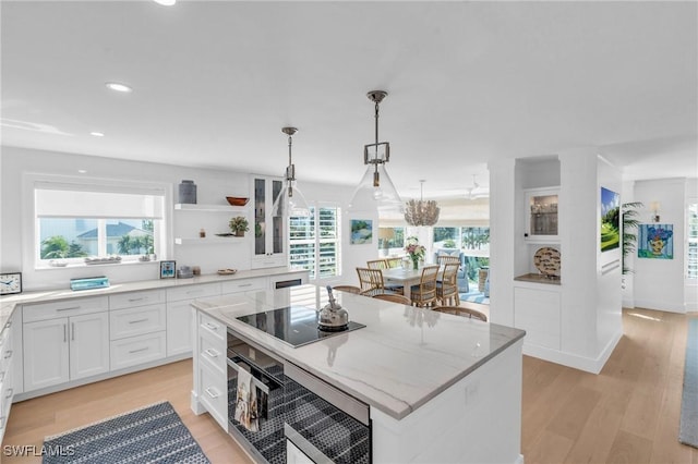 kitchen featuring black electric stovetop, white cabinets, hanging light fixtures, a center island, and open shelves