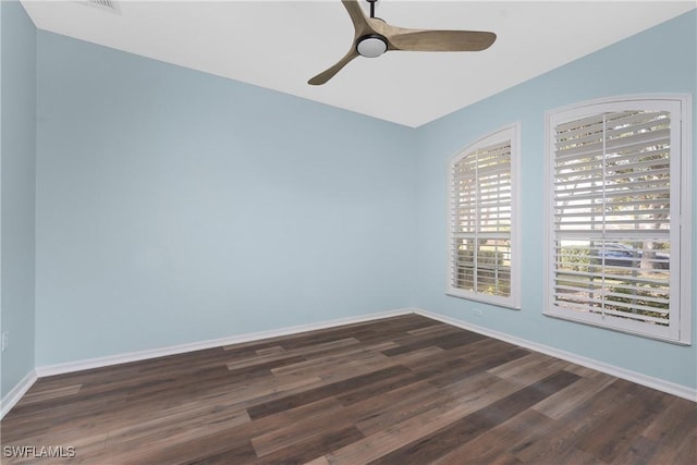 unfurnished room with dark wood-type flooring, a ceiling fan, and baseboards