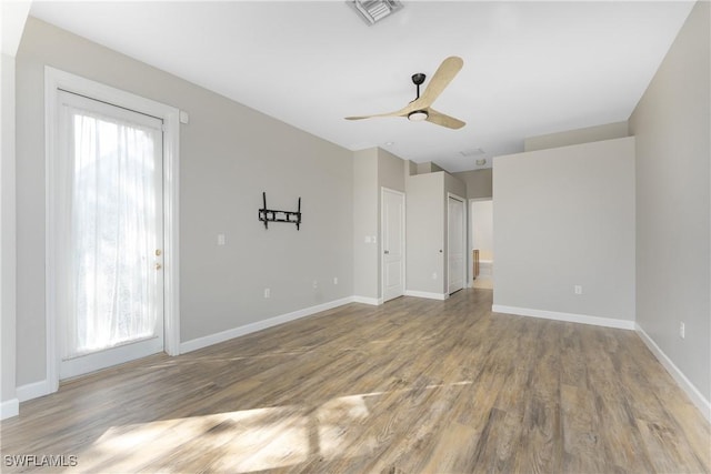 unfurnished room featuring visible vents, wood finished floors, a wealth of natural light, and baseboards