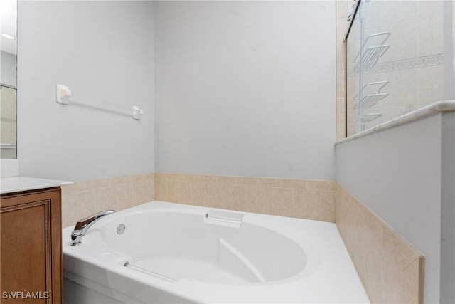 bathroom with vanity and tiled tub