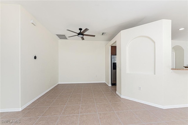 empty room featuring light tile patterned floors, ceiling fan, visible vents, and baseboards