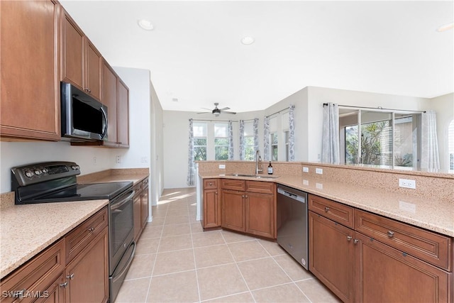 kitchen featuring sink, light tile patterned floors, ceiling fan, appliances with stainless steel finishes, and light stone countertops