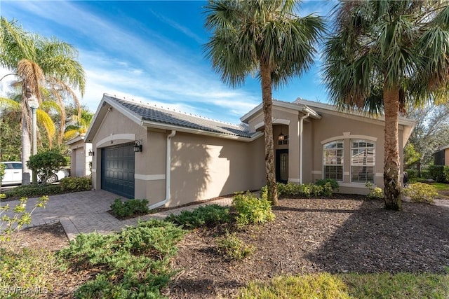 view of front of house featuring a garage, decorative driveway, and stucco siding