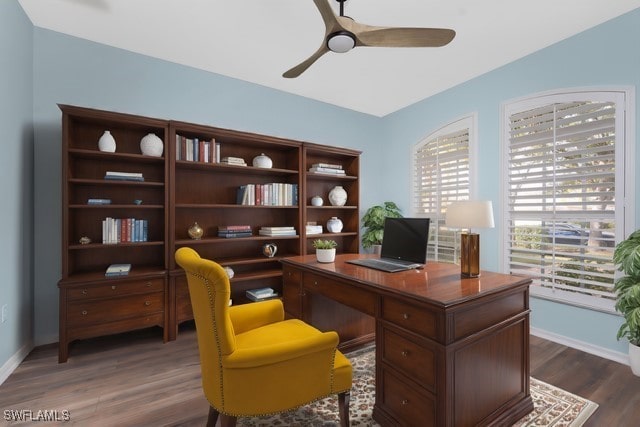 home office with dark wood-type flooring, ceiling fan, and baseboards