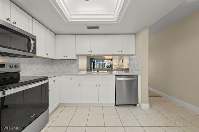 kitchen with stainless steel appliances, a tray ceiling, sink, and white cabinets