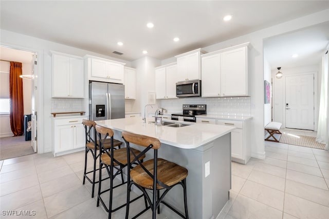 kitchen with appliances with stainless steel finishes, sink, a center island with sink, and white cabinets