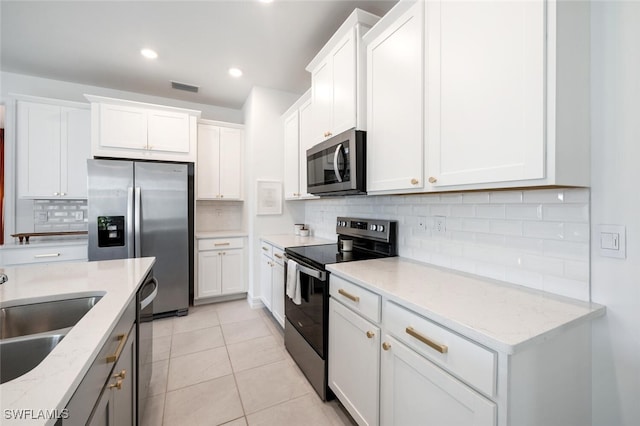 kitchen with appliances with stainless steel finishes, sink, white cabinets, and light stone counters