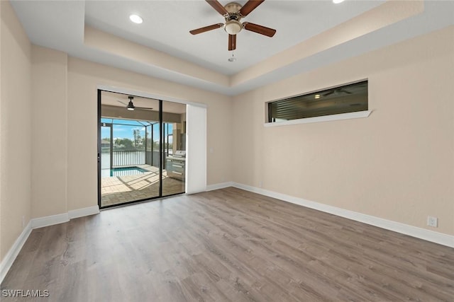 908 SW Embers Ter, Cape Coral, FL 33991 - spare room with a raised ceiling, ceiling fan, wood finished floors, recessed lighting, and a water view