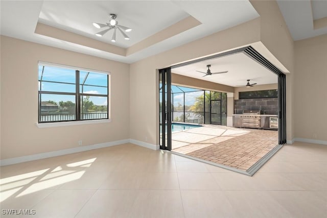908 SW Embers Ter, Cape Coral, FL 33991 - unfurnished room featuring ceiling fan, light tile patterned floors, a tray ceiling, and a sunroom
