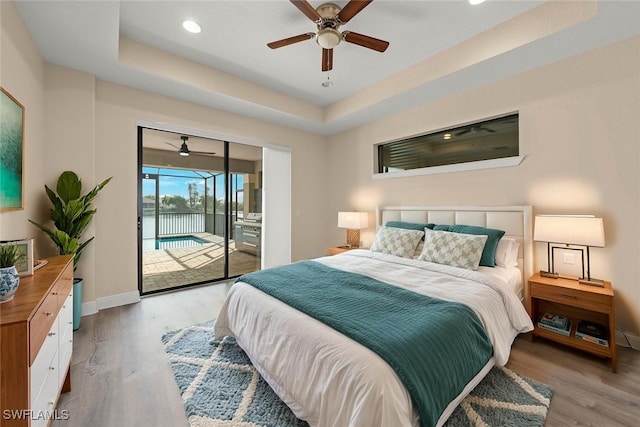 908 SW Embers Ter, Cape Coral, FL 33991 - bedroom featuring access to outside, light wood-style floors, a tray ceiling, recessed lighting, and a water view