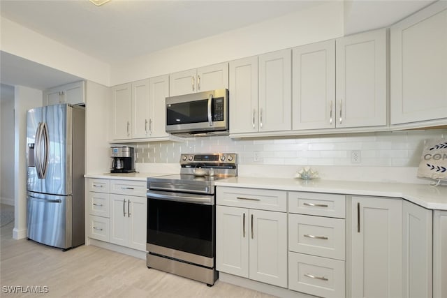 kitchen featuring white cabinetry, appliances with stainless steel finishes, backsplash, and light hardwood / wood-style flooring