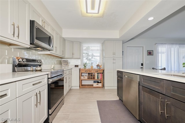 kitchen with sink, white cabinetry, stainless steel appliances, light hardwood / wood-style floors, and decorative backsplash