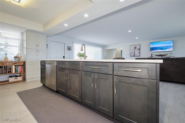 kitchen featuring sink, stainless steel dishwasher, gray cabinets, a kitchen island, and light hardwood / wood-style floors