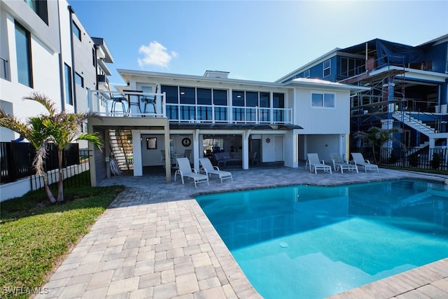 rear view of property with a fenced in pool and a patio area