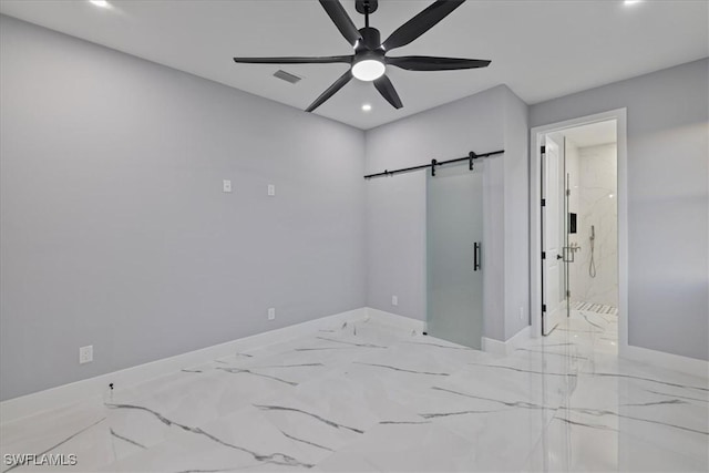 spare room with a barn door and ceiling fan