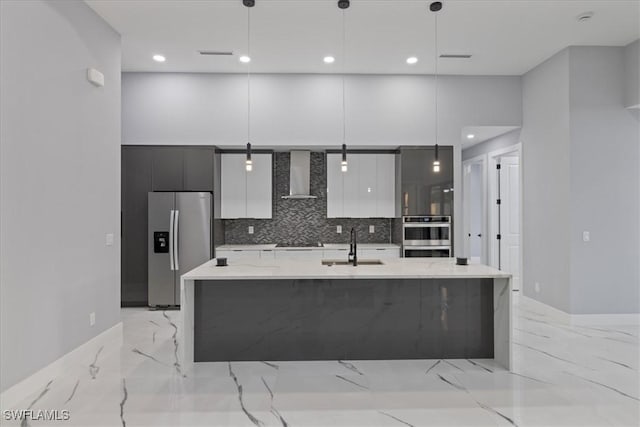 kitchen with pendant lighting, wall chimney range hood, and appliances with stainless steel finishes