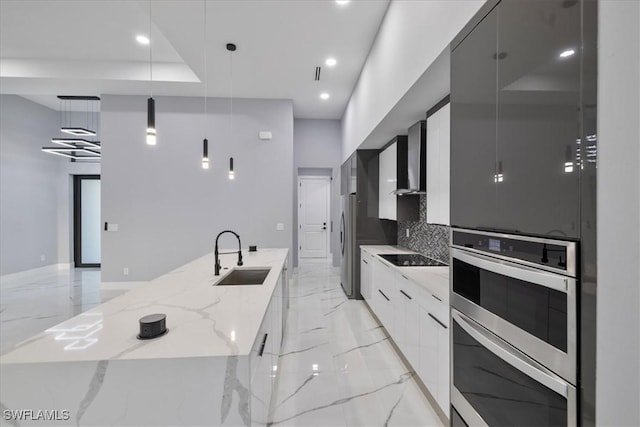 kitchen featuring a large island, hanging light fixtures, sink, and white cabinets