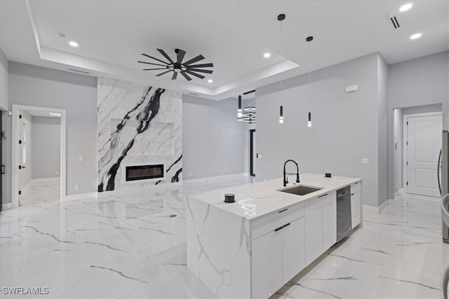 kitchen with sink, white cabinetry, a raised ceiling, pendant lighting, and light stone countertops