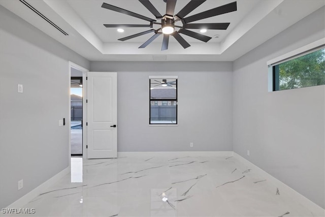 spare room featuring a raised ceiling and ceiling fan