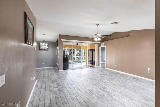 unfurnished living room featuring vaulted ceiling, ceiling fan with notable chandelier, and light wood-type flooring