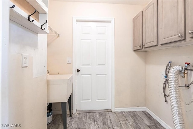 laundry room featuring cabinets, sink, light hardwood / wood-style flooring, and electric dryer hookup