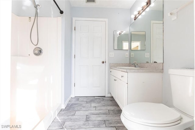 bathroom featuring vanity, a shower, and toilet