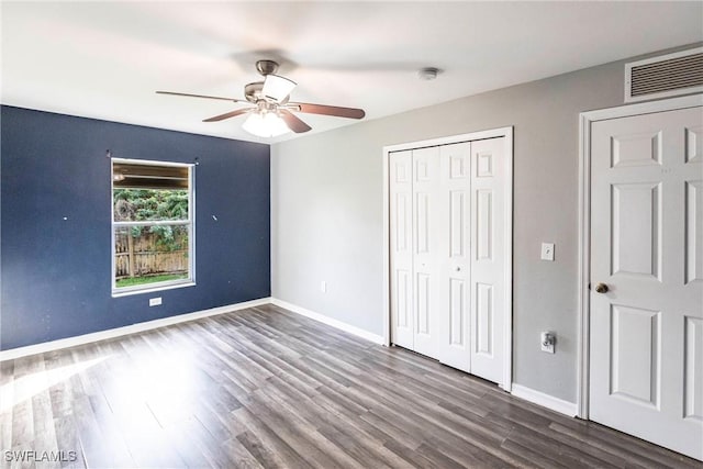 unfurnished bedroom featuring ceiling fan, dark hardwood / wood-style flooring, and a closet