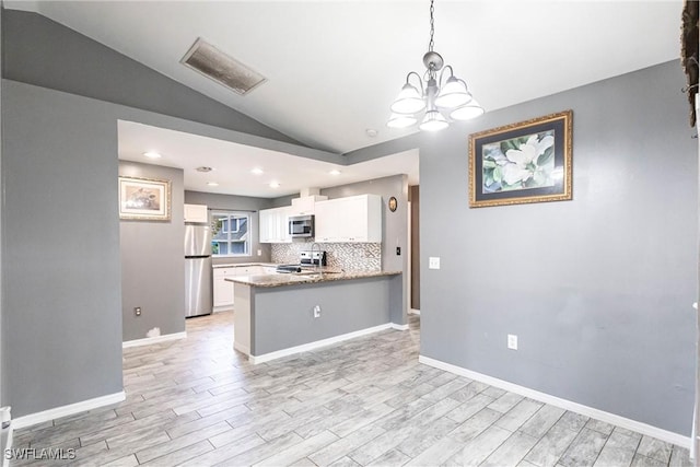 kitchen featuring appliances with stainless steel finishes, decorative light fixtures, tasteful backsplash, white cabinetry, and lofted ceiling