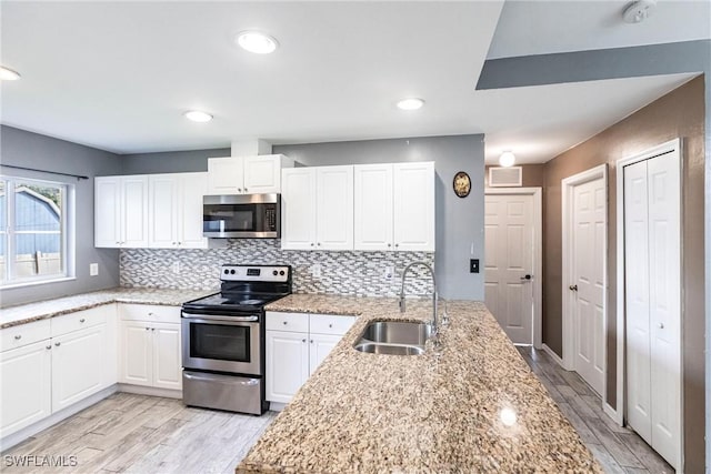 kitchen featuring white cabinetry, sink, stainless steel appliances, and light stone countertops