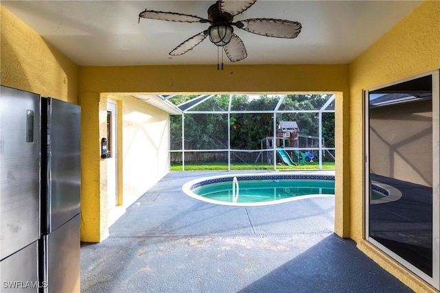 view of pool with a playground, a patio, ceiling fan, and glass enclosure