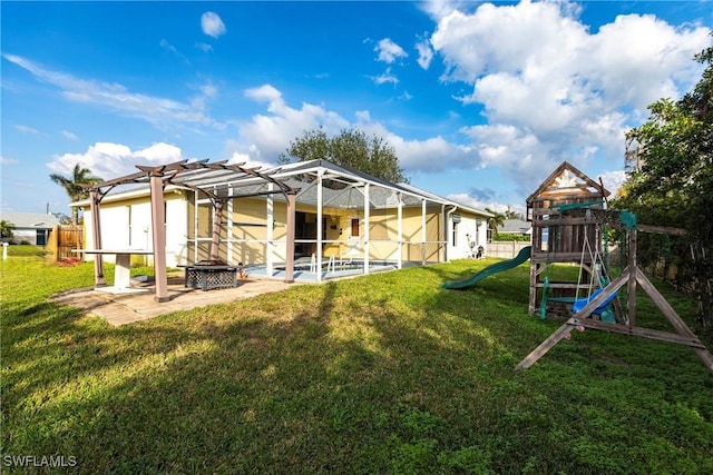 rear view of house with a playground, a patio, a fire pit, a lanai, and a yard