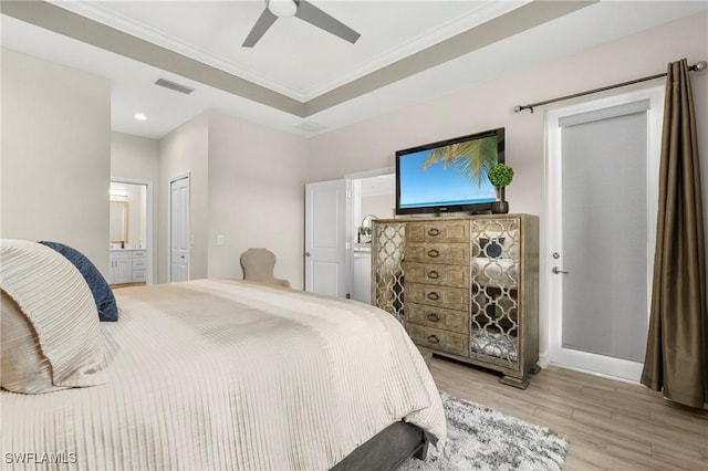 bedroom featuring ensuite bathroom, light wood-type flooring, ornamental molding, a raised ceiling, and ceiling fan